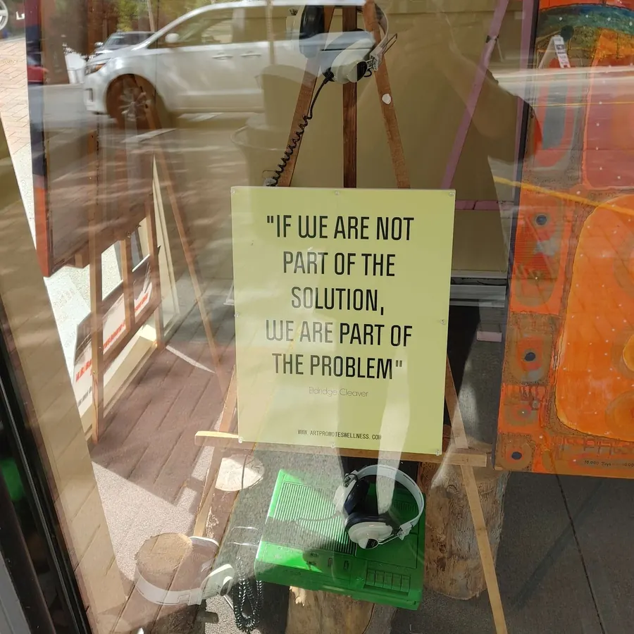 Digital photograph, "Solution or Problem Installation H75300821 (c. 2021) by HB Barry Strasbourg-Thompson. paper sign ELRIDGE CLEAVER quotation, painted tape recorder, 3 earphones, 7 Strasbourg-Thompson Artworks, Easels, Window reflection, Digital photograph.